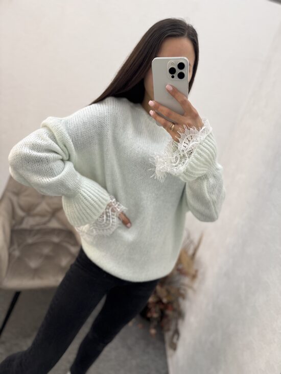 Džemperis ar mežģīni rokas daļā.